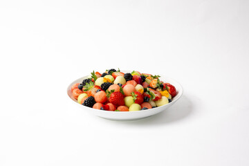 Seasonal fruit salad cut and placed in a lrge white serving bowl.