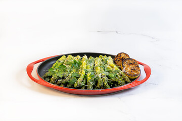 A round serving platter with frilled asparagus, grilled lemons and chopped italian parsley.