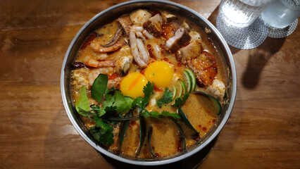 Delicious Tom Yum Hot Pot with Assorted Seafood Pork and Raw Egg in a Flavorful Spicy Broth Served...