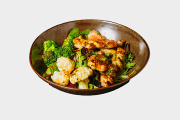 Grilled chicken kakbobs on a bed of mixed green with fresh steamed broccoli and cauliflower