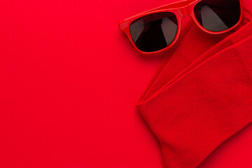 Pair of red socks and sunglasses on bright red background. Top view image of folded red men's socks right side composition. Minimalist flat lay photo of unisex plain red socks with copy space.