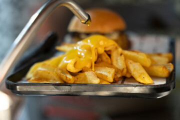 The chef pouring cheddar sauce over the fries