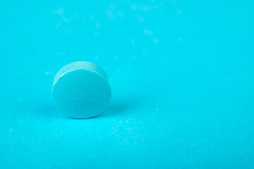 Macro photo of one blue pill of vitamin supplements or drug or painkiller or antibiotic on blue background with copy space.