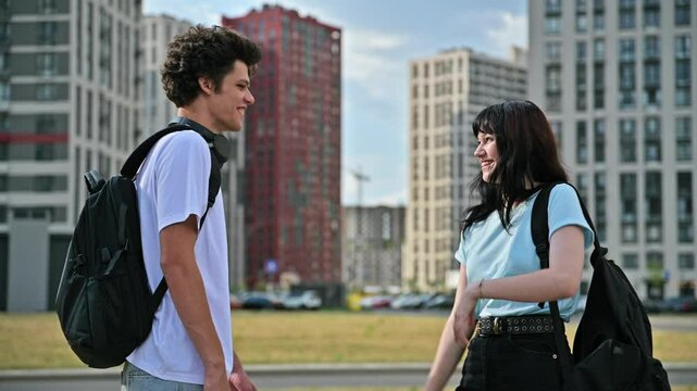 Teenage friends meeting, college university students teenage guy and girl shaking hands, outdoor