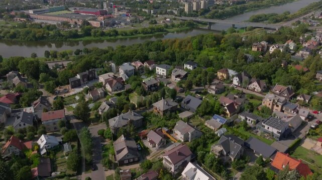 Aerial view of a suburb of Kaunas, Lithuania. The camera is panning smoothly over houses with the Nemunas River and a bridge visible in the background