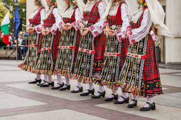 Women dressed in colorful traditional folk costumes dancing in cultural festival