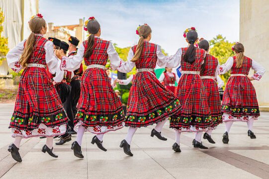 Rear view of group of dancers wearing traditional folk dresses dancing on cultural festival