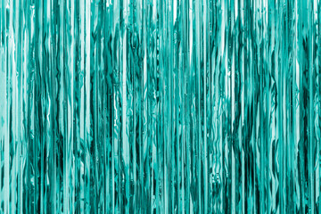 Turquoise foil strip background. Curtain hanging on wall. Festive, Christmas, New Year or anniversary party concept. Decorative wallpaper