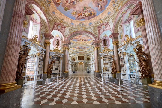 Admont library, Austria, 25 July 2024. A grand baroque library with ornate bookshelves filled with antique books, highlighted by intricate gold detailing
