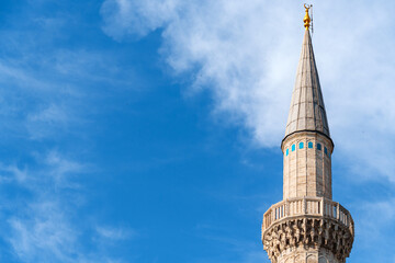 The minaret of the mosque against the background of a blue sky with clouds, the architecture of the...