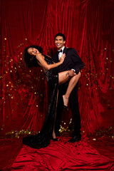 Photo of beautiful bonding couple hollywood stars posing in ceremony isolated over red color...