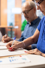 Middle aged person signing the agreement contract with the bank, ensuring their pension and life savings. Giving the signature on document for future financial security. Close up.