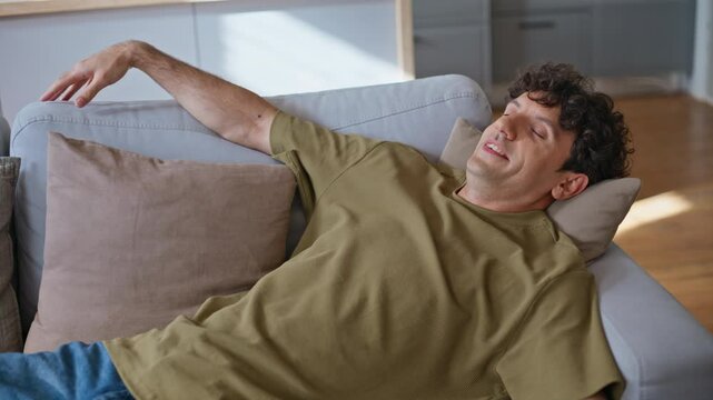 Closeup guy falling couch feeling happy at home. Lazy man taking rest chilling