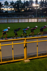 Motion photography of some racing skaters training on skate track at sunset