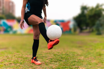 View of legs of brunette female soccer player running to kick soccer ball. on a green grass...