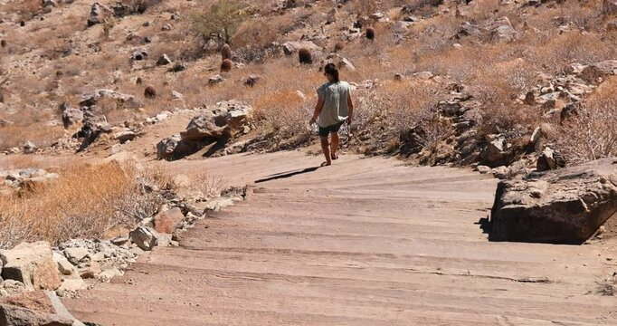 Phoenix Arizona Victory Stairs hiking trail woman. Desert landscape and environment. View point above city. Wooden steps to the top of a dry cactus with volcanic cinder cone and granite mountain.