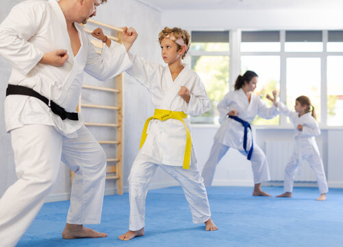 Father and son karatekas in kimonos practice karate fighting in studio