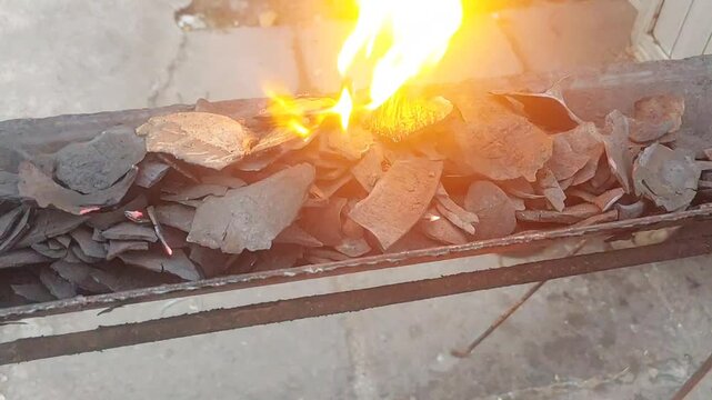 Close up shot of burning coconut shell charcoal fire. Slow motion of burning fire, red and yellow flames. Coconut shell, charcoal in charcoal grill. Cooking over charcoal