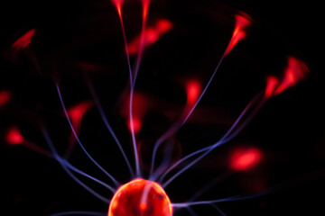 A glowing plasma ball with red and blue energy arcs radiating against a dark background, creating a vivid and electrifying visual effect