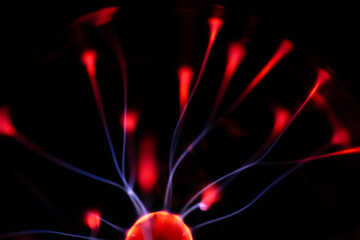 A glowing plasma ball with red and blue energy arcs radiating against a dark background, creating a vivid and electrifying visual effect