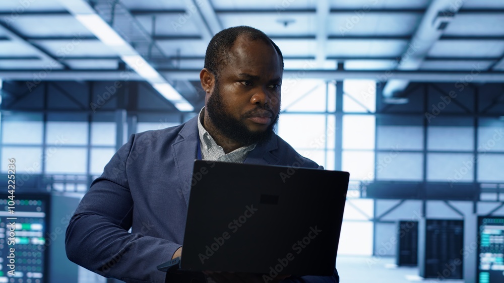 Poster computer scientist in data center using diagnostic tools and system monitoring software on laptop to