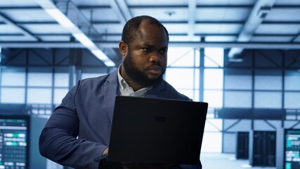 Computer scientist in data center using diagnostic tools and system monitoring software on laptop...