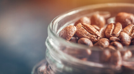 Beautiful coffee beans close-up, lying in a jar with a ray of morning sun falling on them
