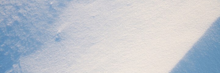 Obraz premium Beautiful winter background with snowy ground. Natural snow texture. Wind sculpted patterns on snow surface. Wide panoramic texture for background and design. Closeup top view with copy space.