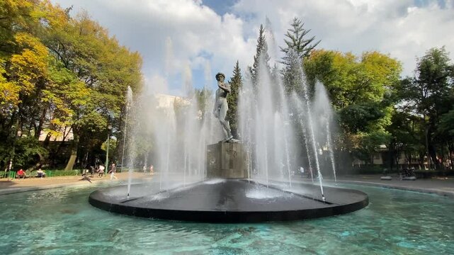 Rio de Janeiro square, located in colonia Roma neighborhood in Mexico City, Mexico. A replica of Michelangelo's David statue surrounded by a water fountain is seen.