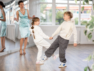 Happy couple of preteen dancers in sportswear practicing vigorous lindy hop at dance rehearsal with...