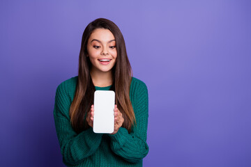 Portrait of pretty young girl show empty space phone screen wear sweater isolated on violet color background