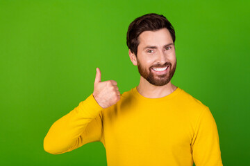 Fototapeta premium Photo of satisfied man with stylish beard dressed yellow shirt showing thumb up approve good job isolated on green color background