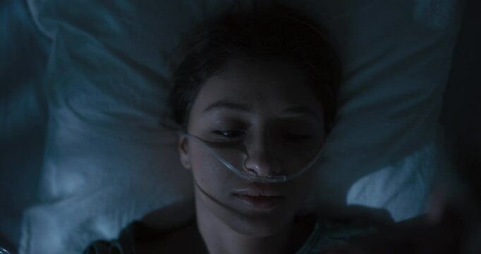 Young girl patient wakes up in a hospital room after a nightmare, lying with an oxygen tube in her nose.
