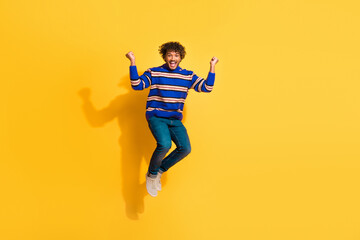 Full length photo of handsome young guy jumping winning dressed stylish blue striped garment...