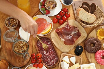 Woman eating different food during brunch at wooden table, top view