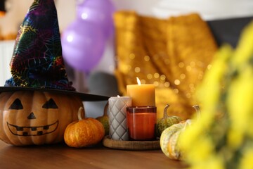 Burning candles and pumpkins on wooden table indoors. Halloween celebration