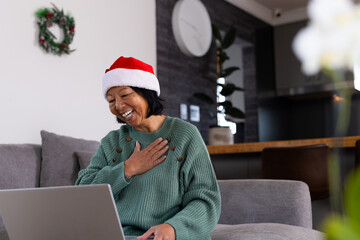 asian senior woman wearing Santa hat video chatting at home, smiling warmly, Christmas time