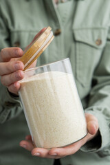 Woman holding Raw semolina porridge in sustainable natural packaging. Refillable glass jar. Gluten...