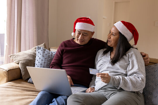 Christmas time, senior multiracial couple shopping online with laptop and credit card