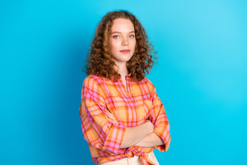 Confident young woman with curly hair standing against a bright blue background, expressing a...