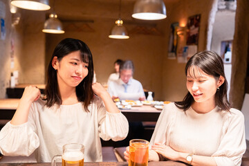 居酒屋で女子会をする二人の女性