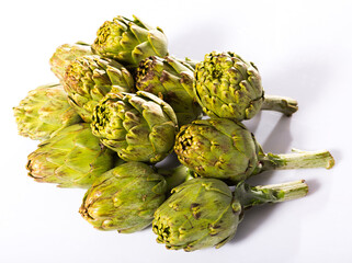 Fototapeta premium Uncooked green artichokes on a white surface. High quality photo