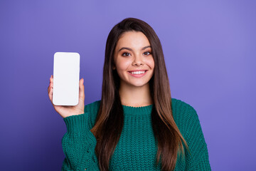 Portrait of pretty young girl show empty space smart phone screen wear sweater isolated on violet...