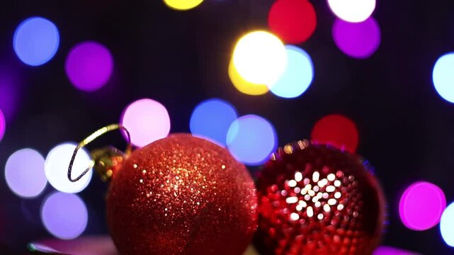 Una toma de cerca de dos bola de navidad roja rodeada de luces de varios colores con un fondo desenfocado.  Decoraci&oacute;n de navidad y fin de a&ntilde;o
