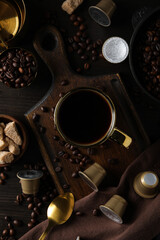 Coffee capsules, coffee beans, and cup on wooden background, top view