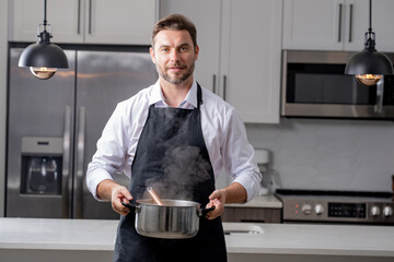 modern chef in professional uniform. close-up on the hand of male chef who is stirring soup in pot...