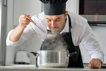 chef stirring a pot of aromatic soup with ladle. Chef cook in uniform cooking soup in the big...