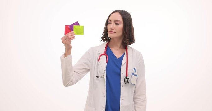 Woman gynecologists shows condoms and thumbs up gesture against white. Female medic with stethoscope demonstrates contraception methods