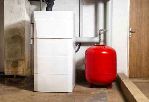 Oil condensing boiler with expansion vessel in boiler room or basement. Oil fired condensing boiler with pump, fan and pressure sensor. Heating system in residential building. Selective focus.