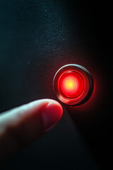 Finger on a red illuminated push button.